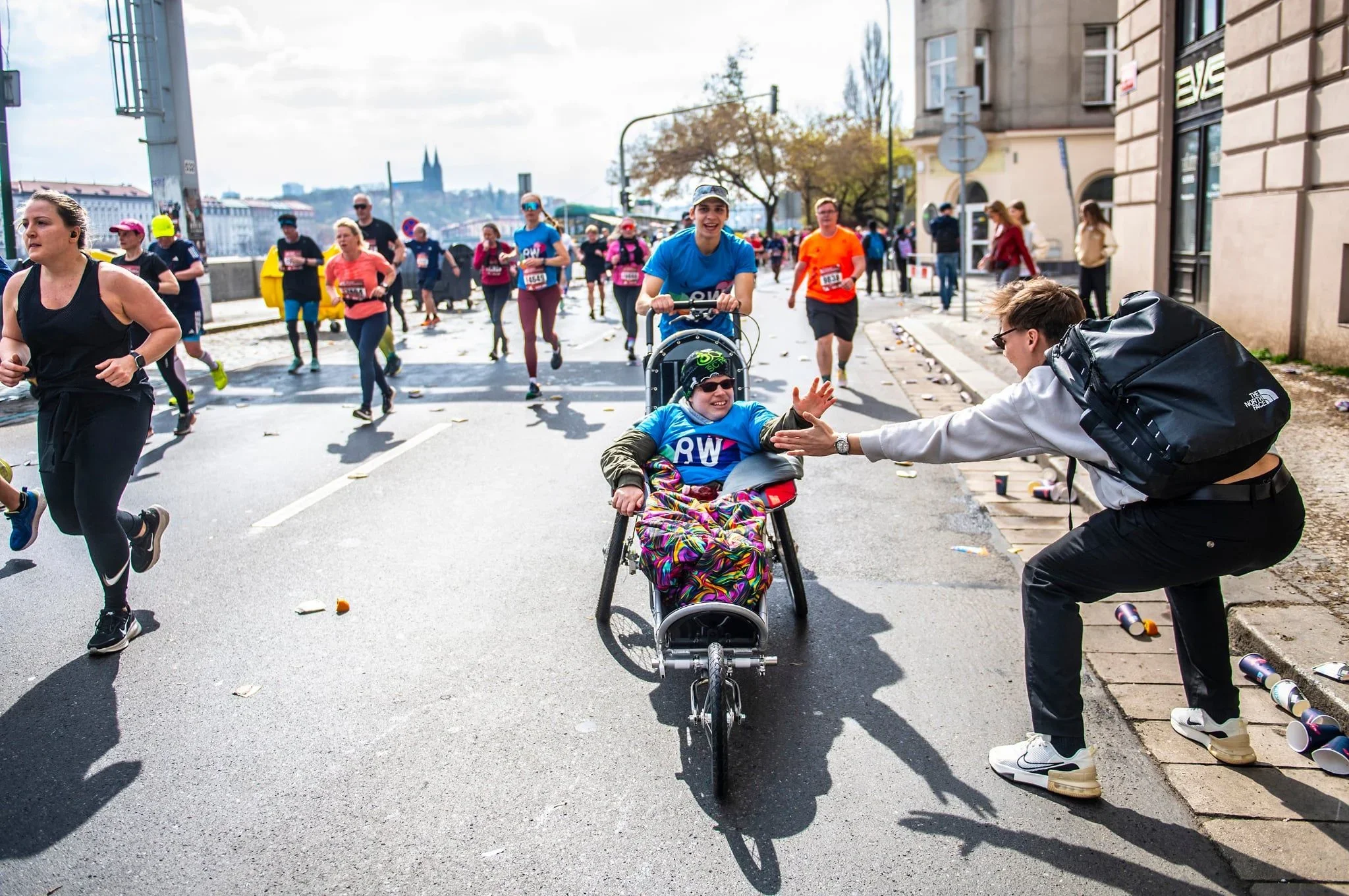 Divák si plácá s dítětem ve vozíku na trati půlmaratonu